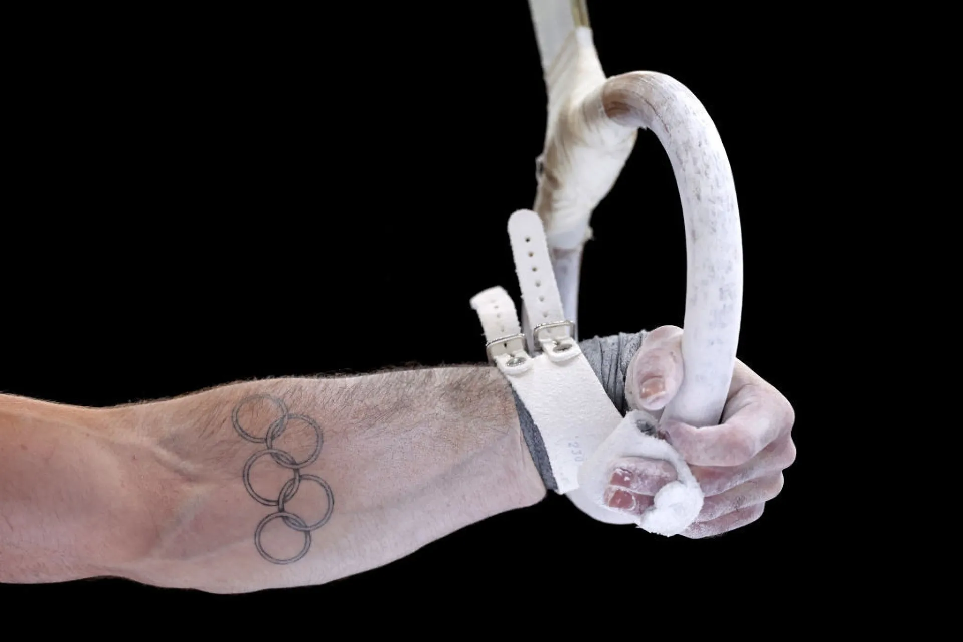 Atleta exibindo com orgulho uma tatuagem dos anéis olímpicos em seu braço.