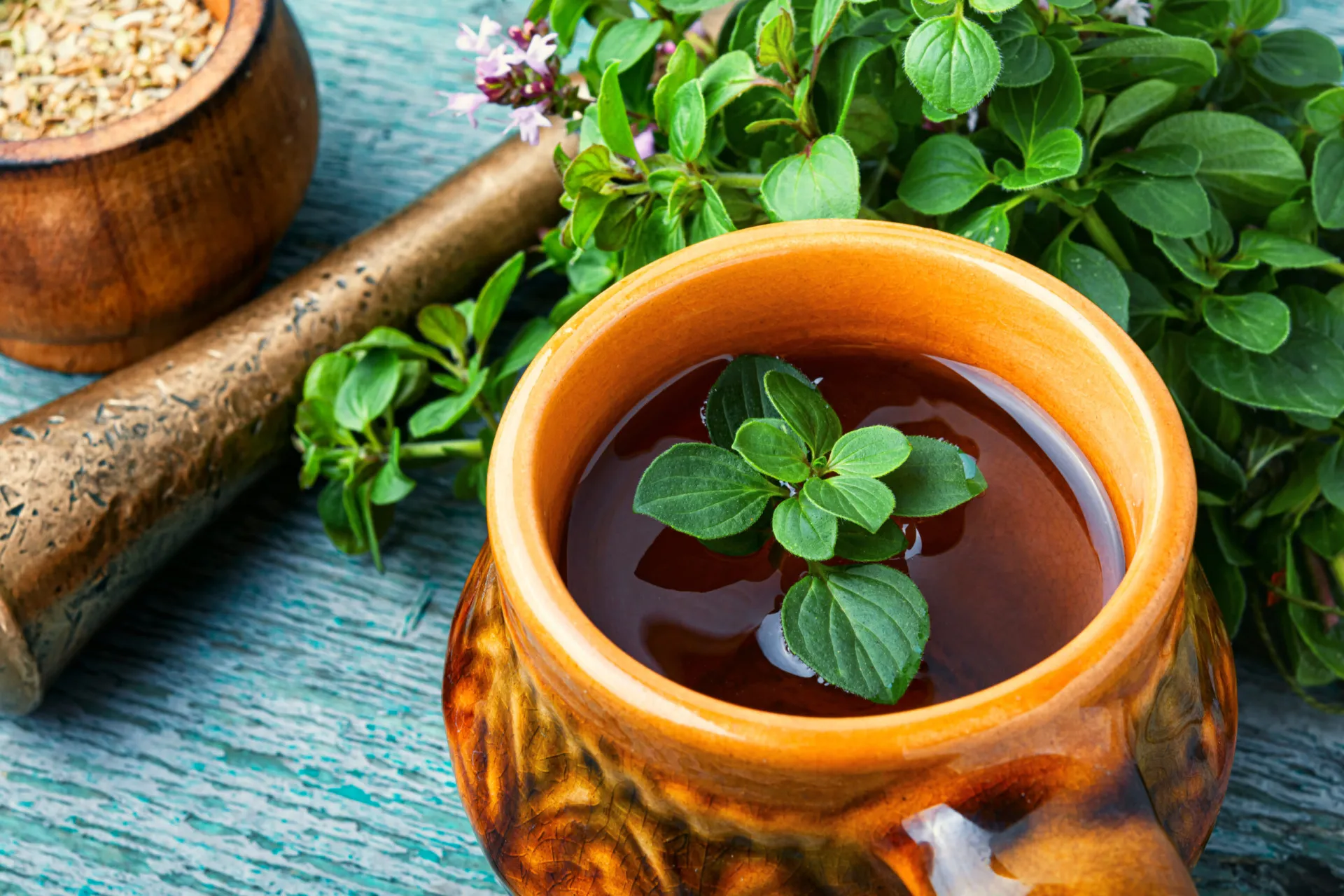 Chá de manjerona em uma xícara, com a erva seca ao lado para infusão.