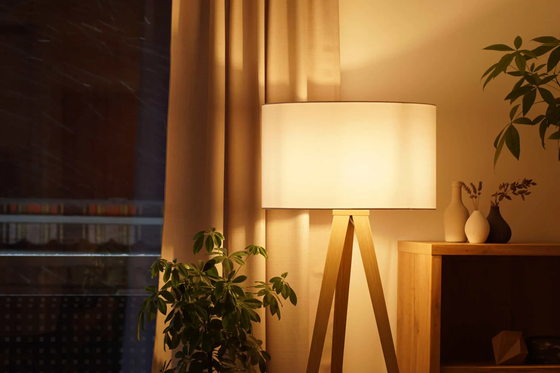 Abajur com cúpula de linho claro iluminando suavemente um canto da sala.