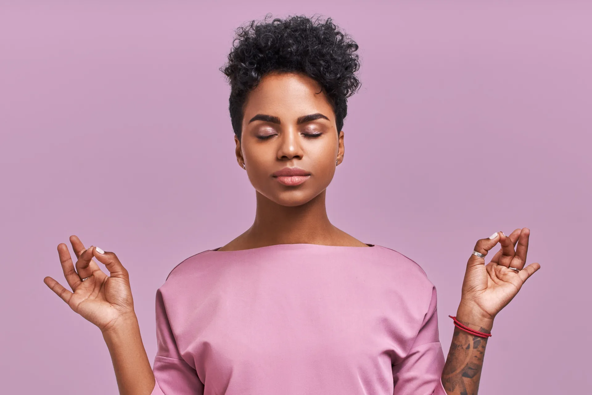 Mulher sorrindo e relaxada, sentada em um tapete de yoga, sentindo-se bem.