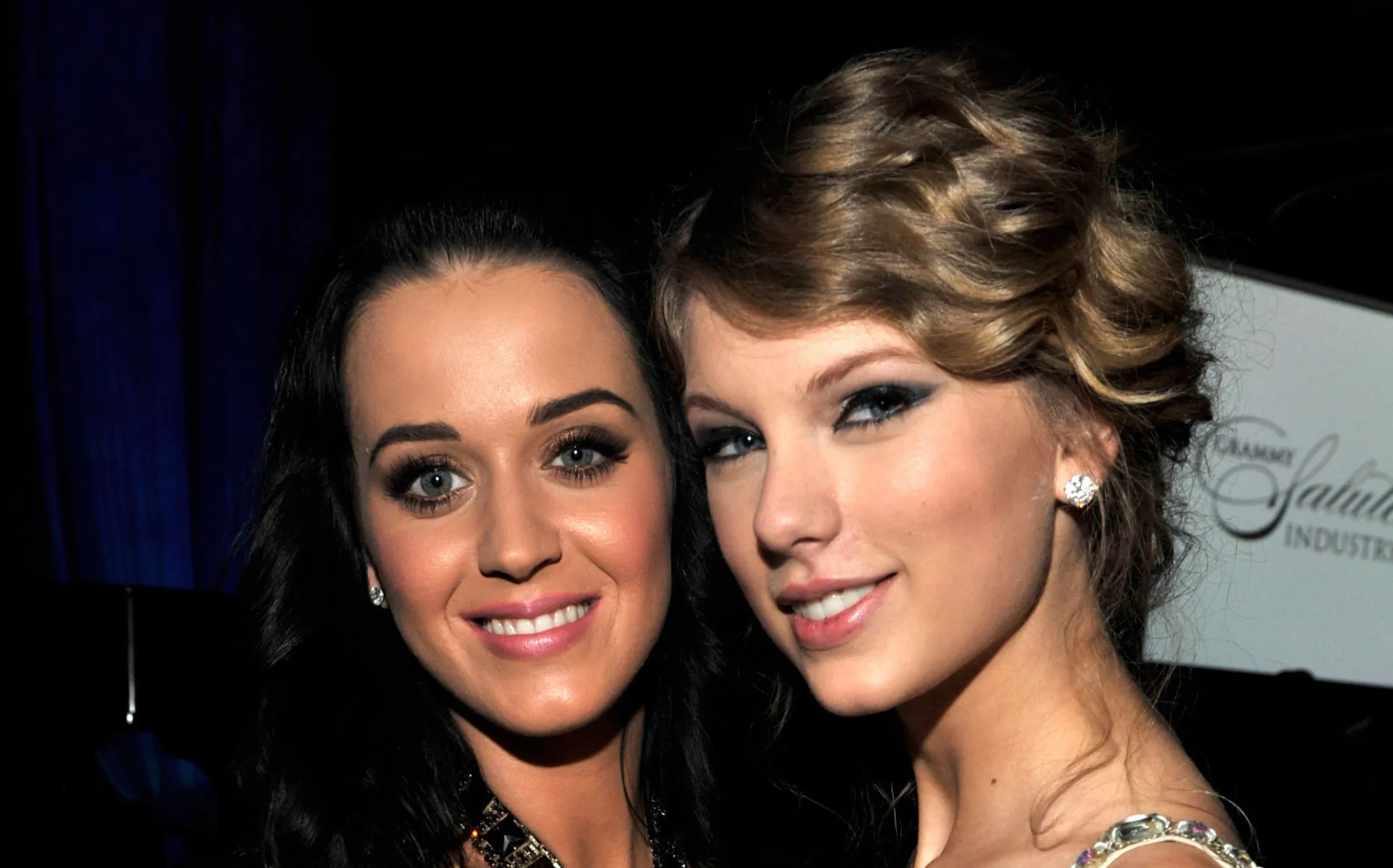 Taylor Swift e Katy Perry lado a lado, com expressões sérias, representando sua rivalidade.