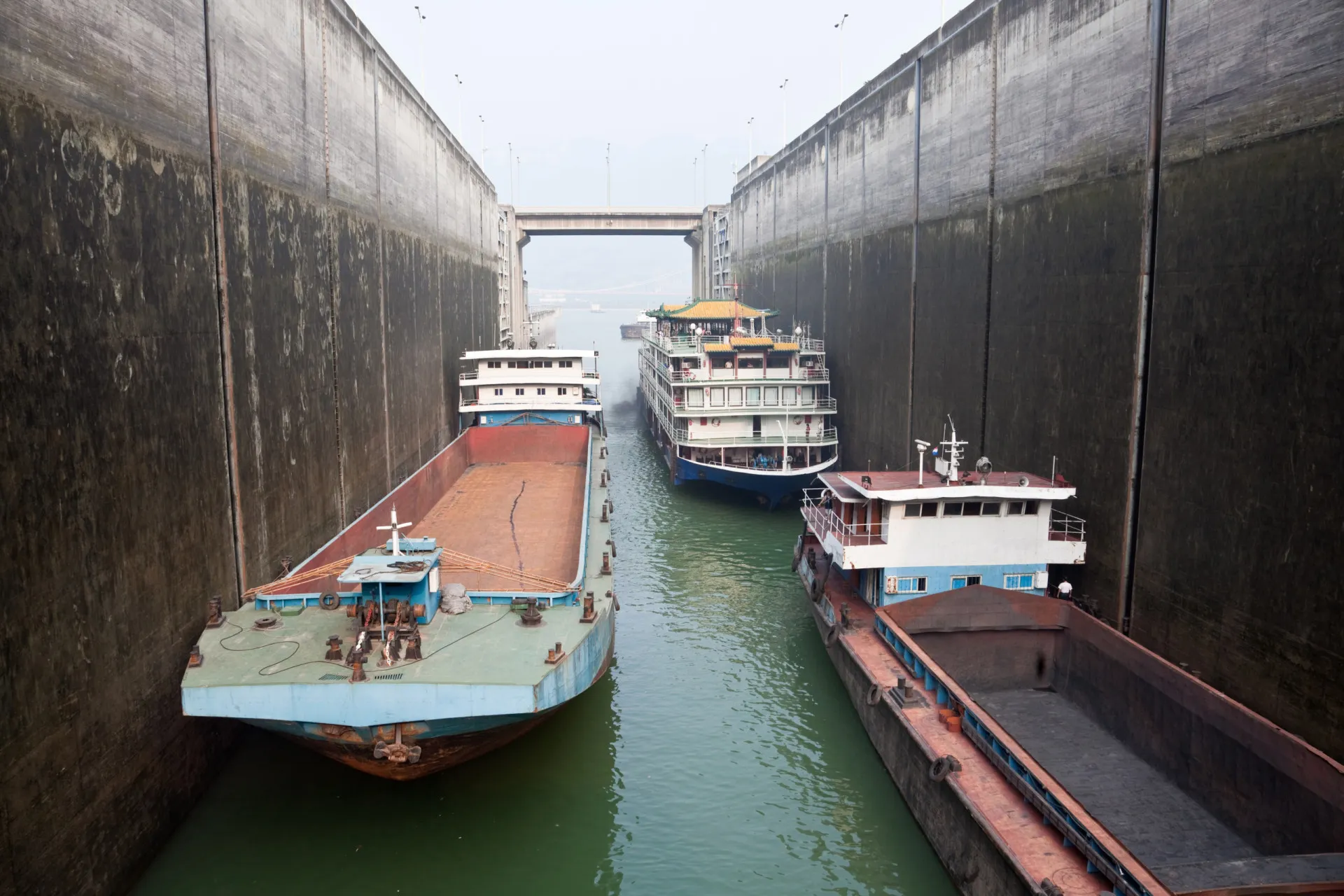 Navios de carga navegando tranquilamente pelo Rio Yangtzé, perto da barragem.