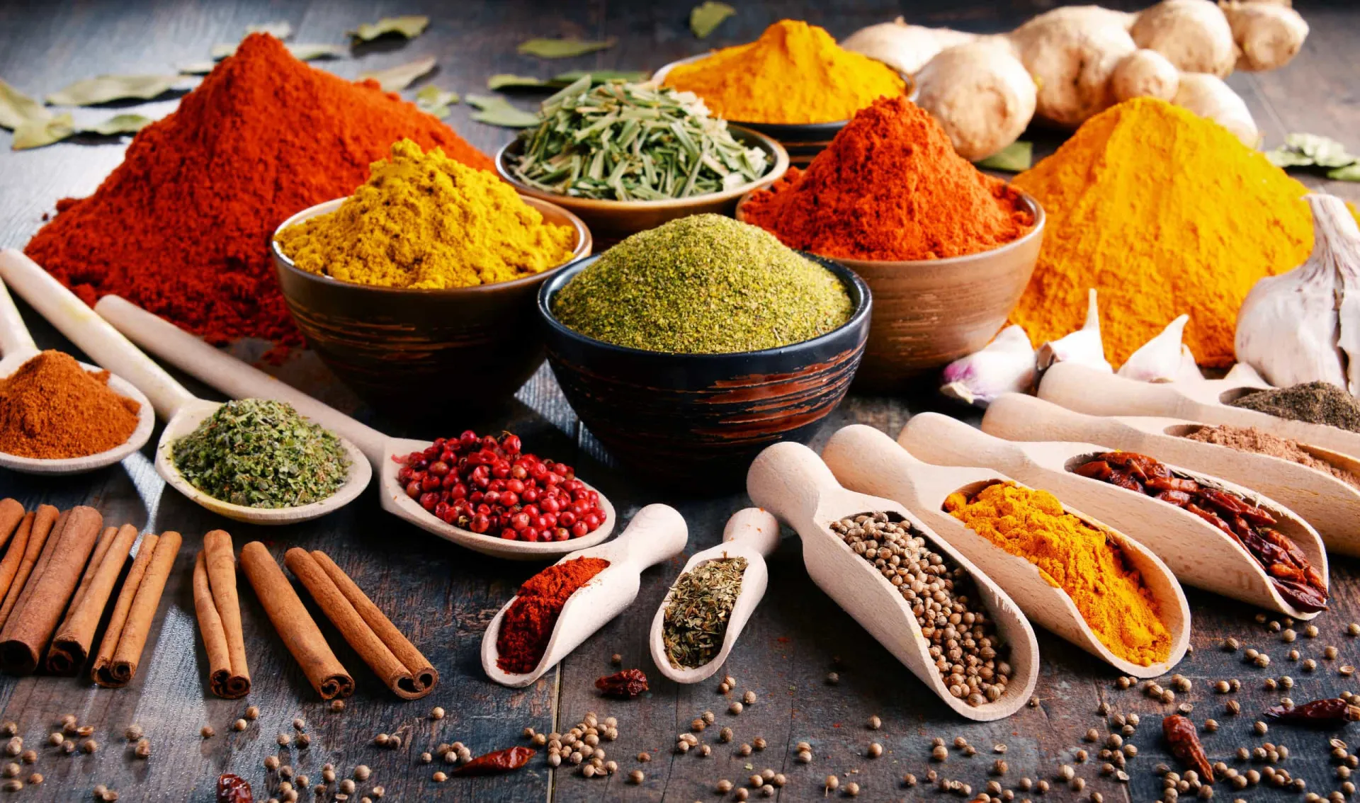 Uma variedade de especiarias coloridas como cúrcuma, canela e gengibre em pó.