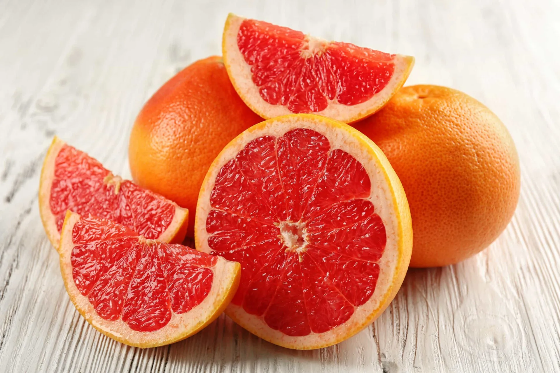 Várias frutas cítricas como laranjas, limões e toranjas, cortadas e inteiras.