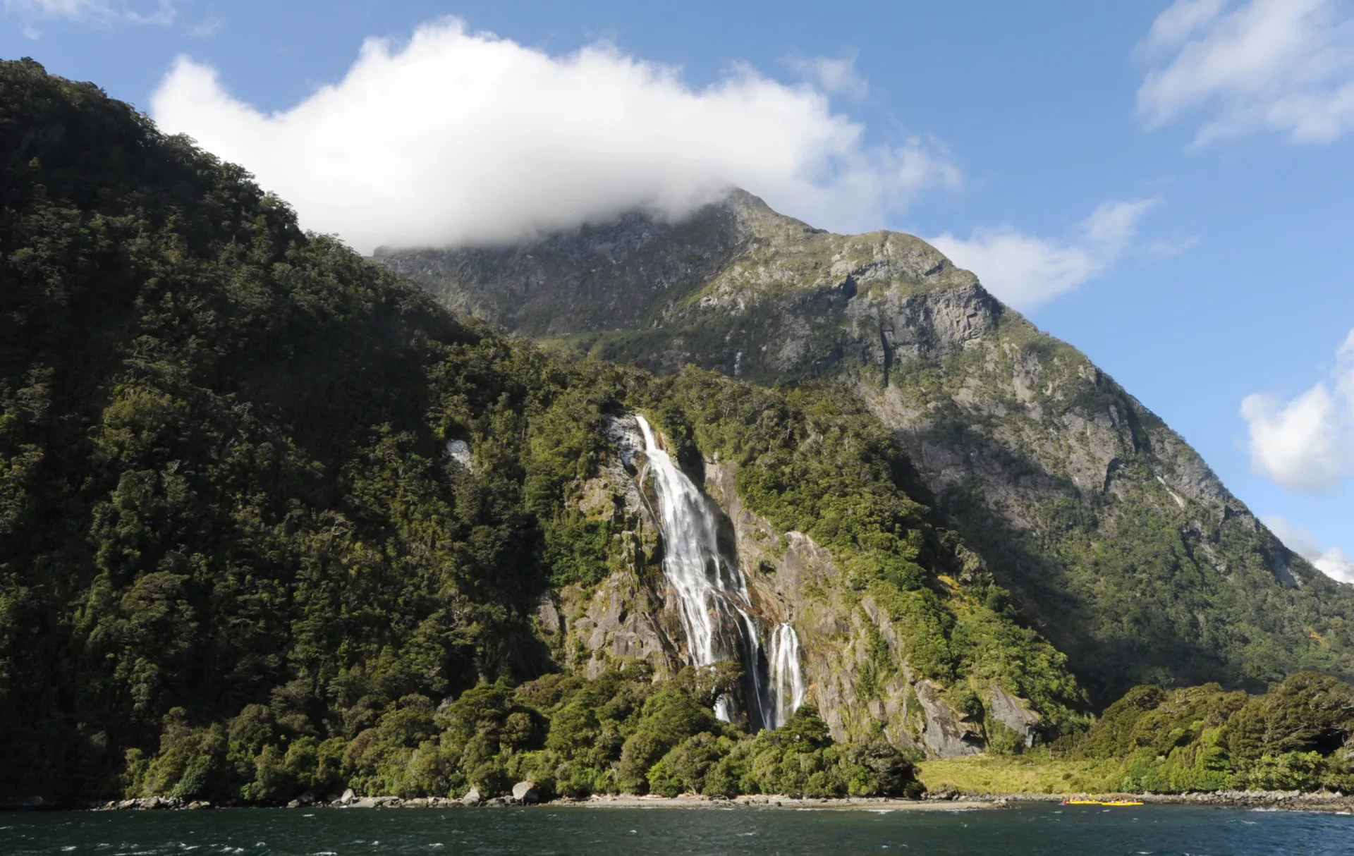 Paisagem épica da Nova Zelândia, com montanhas, lagos e campos verdes.