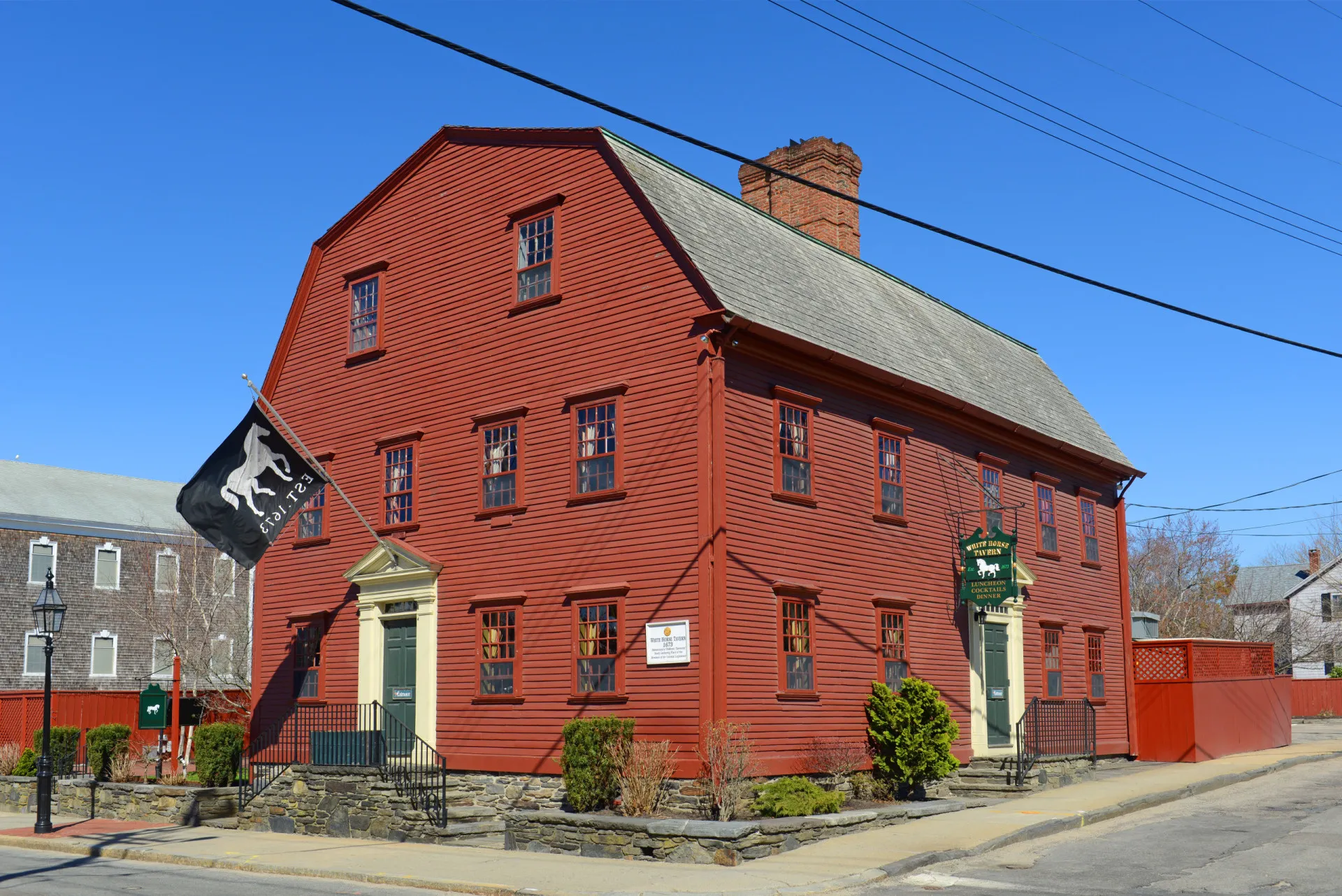 A icônica fachada vermelha da The White Horse Tavern em Newport, Rhode Island, com sua placa de cavalo branco.