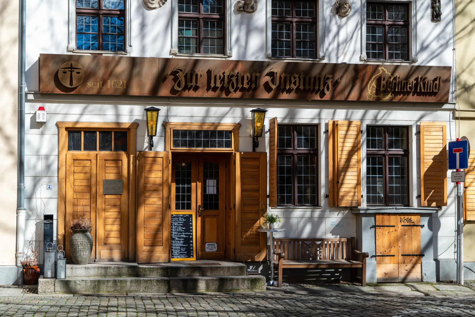 Interior do Zur letzten Instanz em Berlim, um restaurante rústico com vigas de madeira e uma antiga estufa de cerâmica.