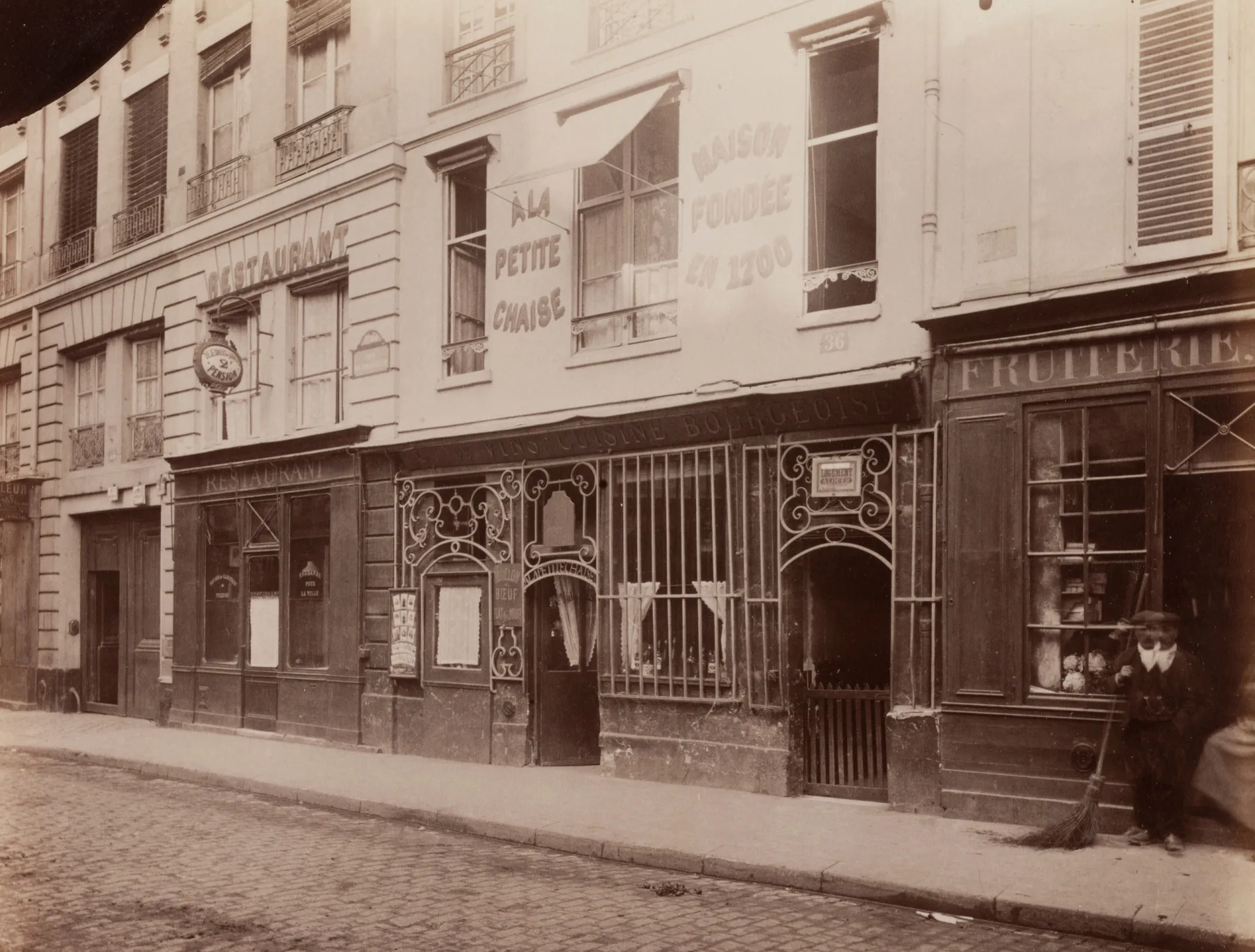 Fachada do La Petite Chaise em Paris, um charmoso restaurante com uma porta azul e lanternas antigas.