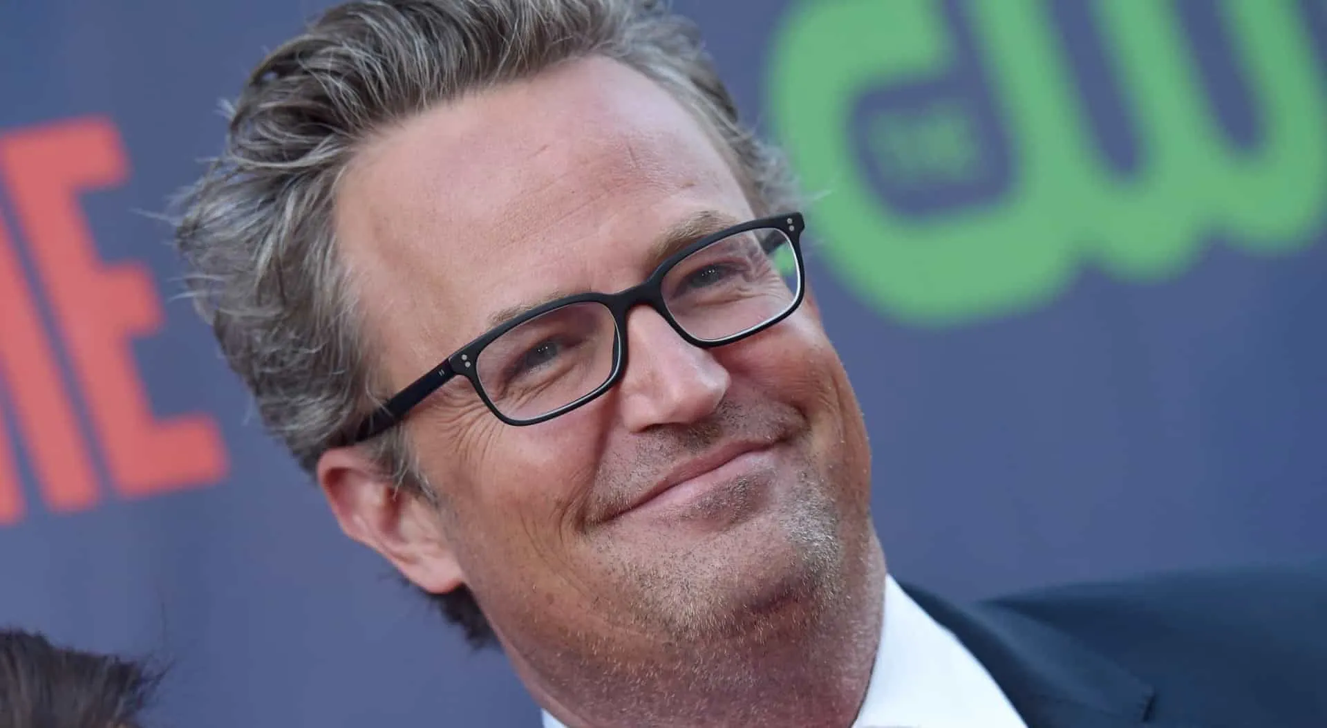 Matthew Perry sorrindo, lembrado por seu papel icônico como Chandler Bing em 'Friends'.