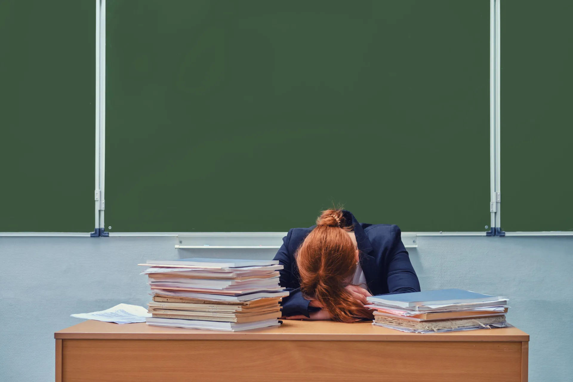 Estudante com um capelo de formatura e uma bola de ferro com corrente presa ao pé, simbolizando a dívida estudantil.
