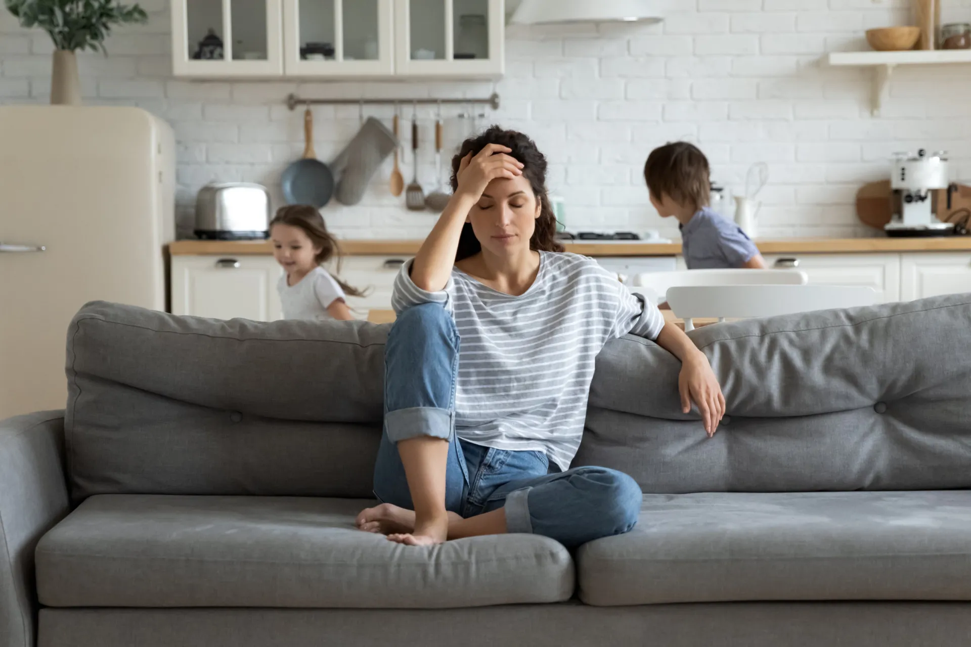 Mãe segurando um bebê enquanto trabalha no computador, mostrando a falta de licença parental.