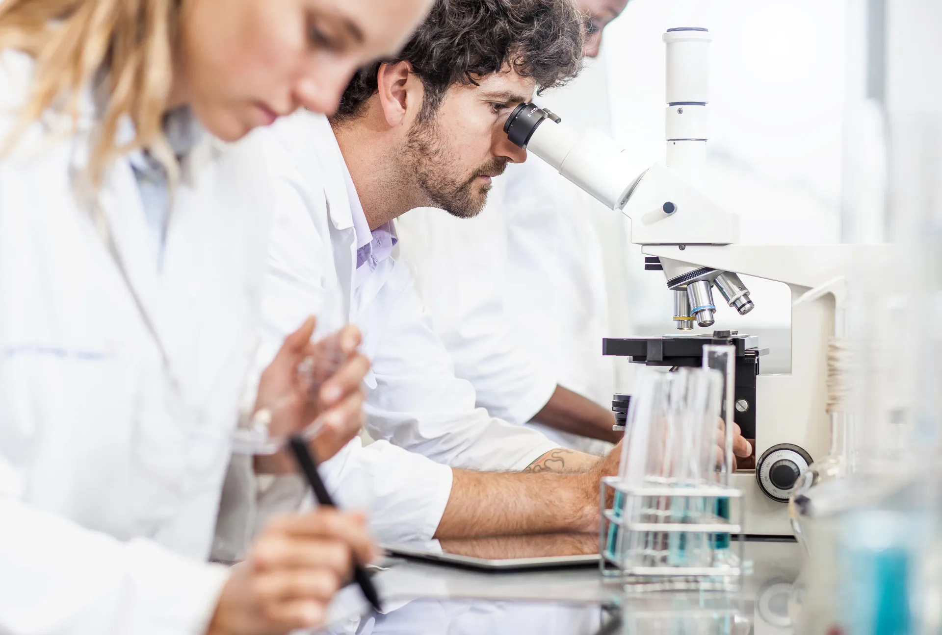 Cientista em um laboratório observando uma placa de Petri com células.