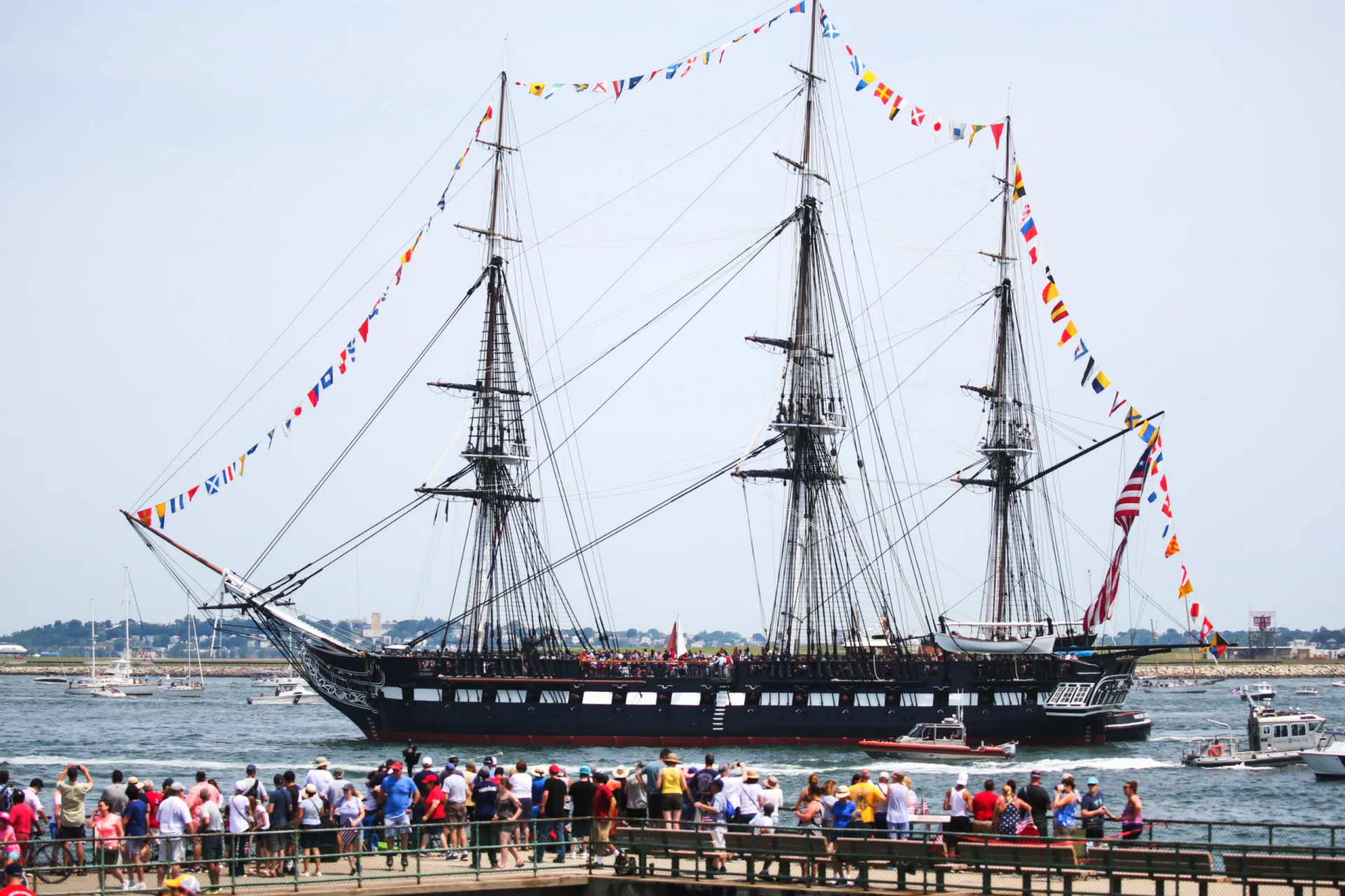 O USS Constitution, uma fragata de madeira de três mastros, navegando com suas velas enfunadas.
