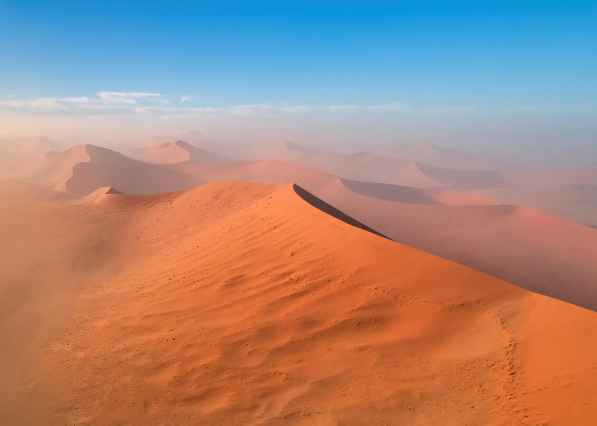 Dunas de areia vermelha do Deserto do Namibe encontrando o Oceano Atlântico.
