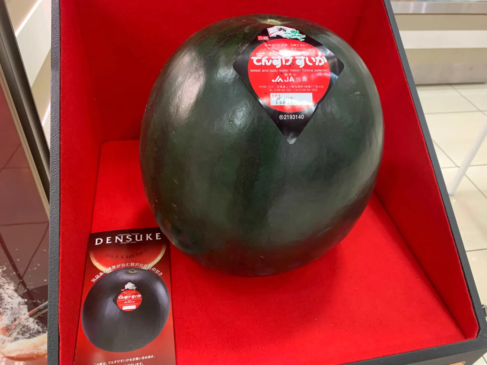Uma melancia Densuke inteira, com sua casca preta e brilhante, em um mercado.