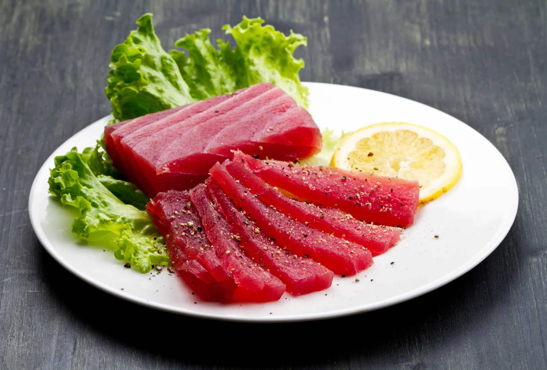 Um chef japonês cortando um grande pedaço de atum-rabilho fresco para sushi.