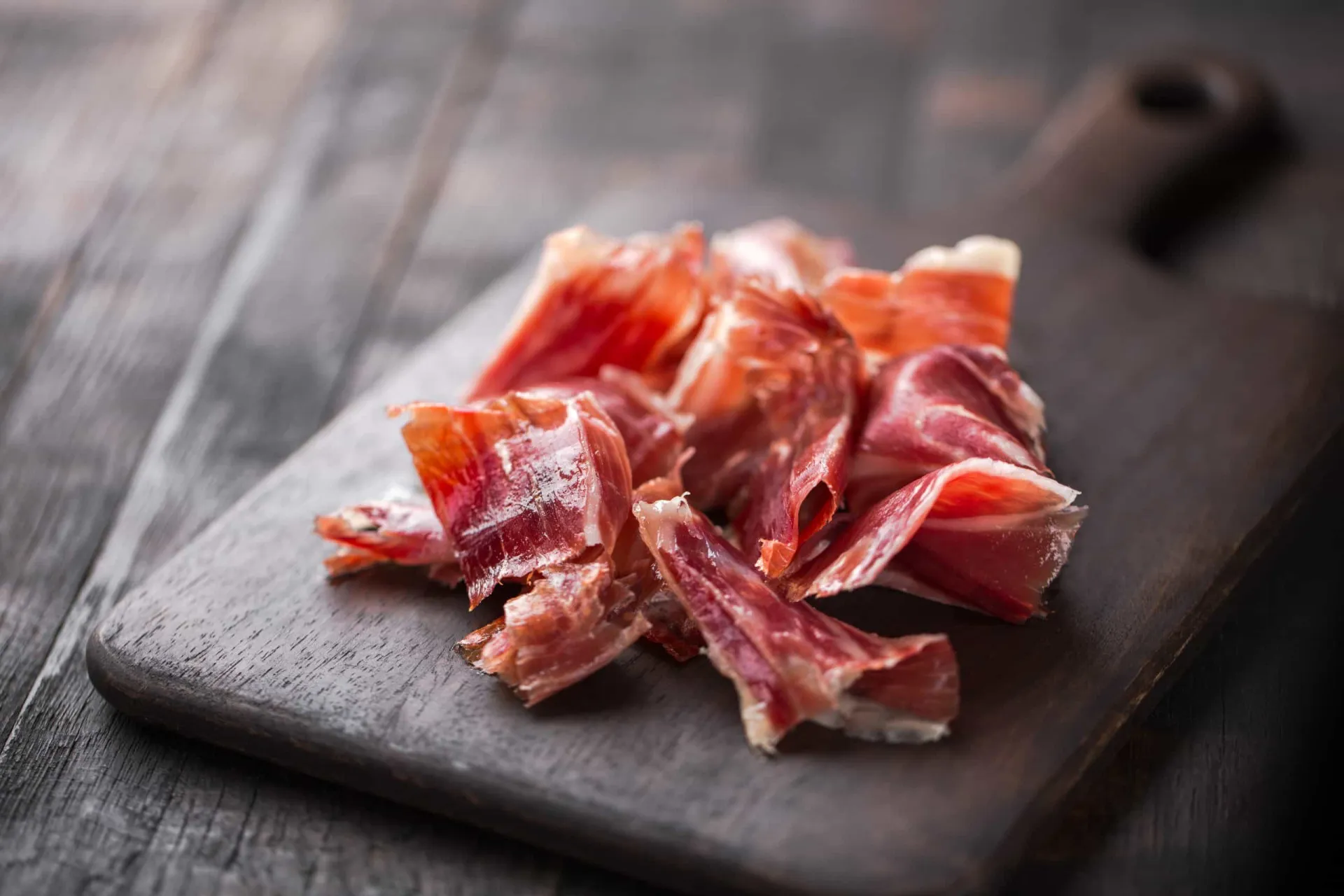 Uma perna de presunto ibérico sendo fatiada por um profissional.
