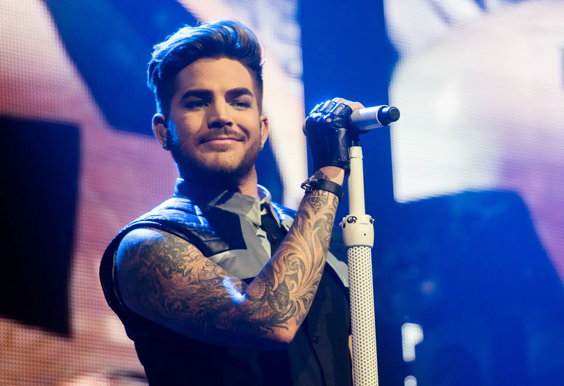 Adam Lambert no palco, com sua presença marcante e visual glam rock.