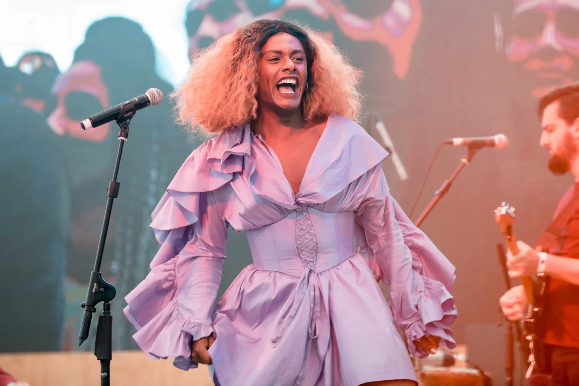 Cantora Liniker cantando em um show com microfone na mão.