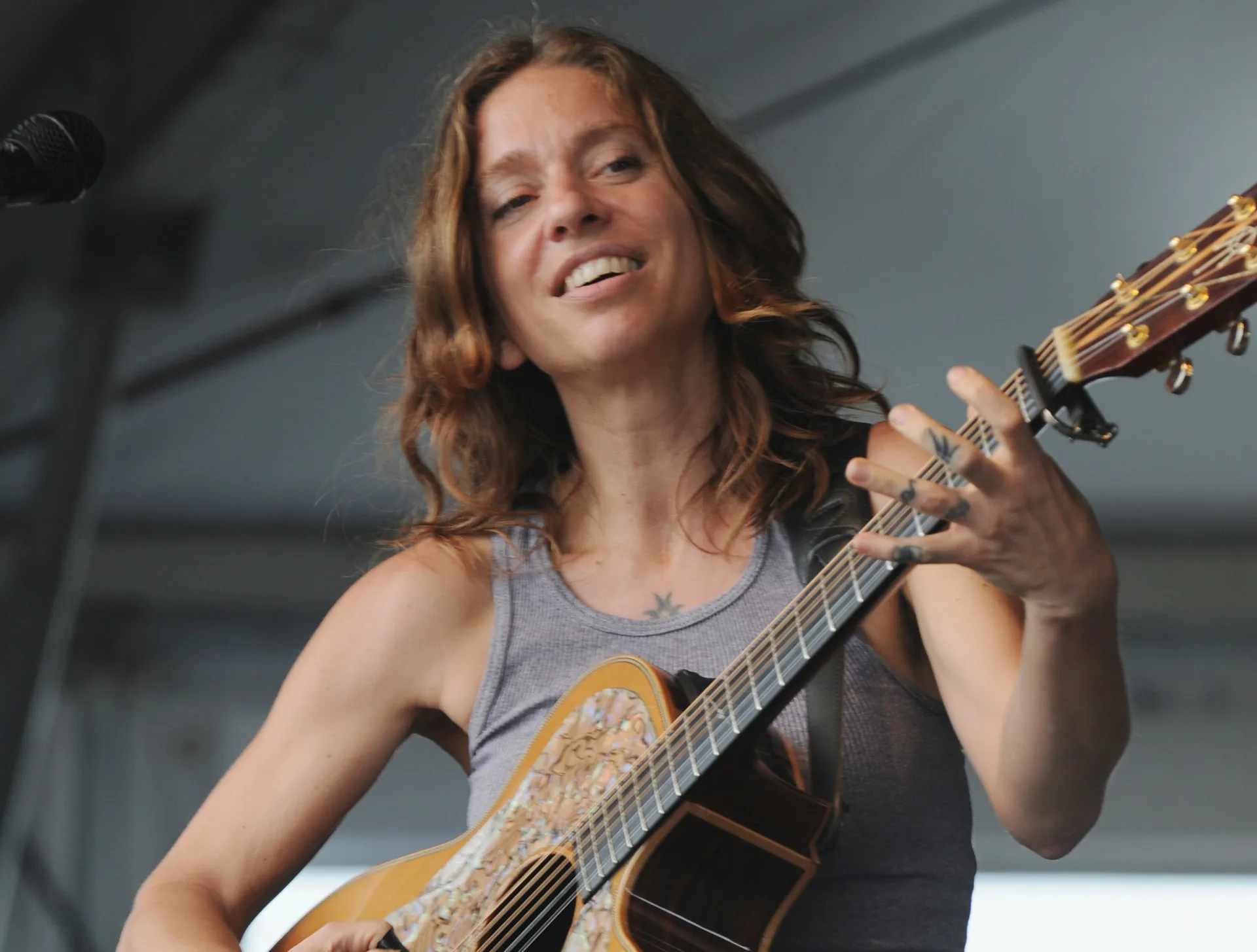A cantora e ativista Ani DiFranco com seu violão, em uma performance enérgica.